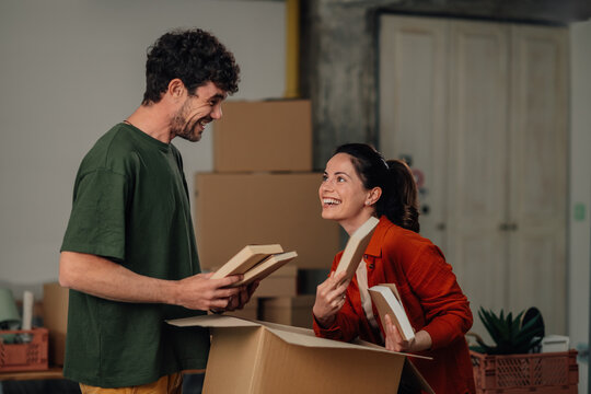 Happy couple unpacking books in new home - Powered by Adobe