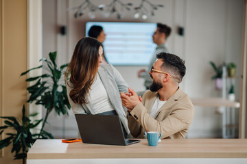 Business colleagues holding hands and laughing at the office