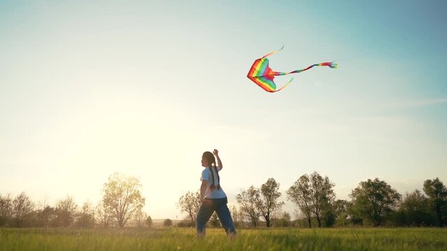 Person flying in field. Silhouette of young girl holding kite while running. Girl is running with a kite and a kite. An individual manipulating a kite in lifestyle a meadow.