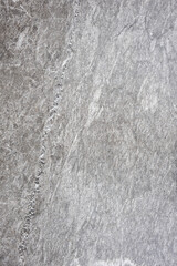 Close-up of grey stone surface with natural texture and diagonal crack.