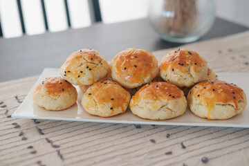turkish savory pastry pogaca with dill and black sesame or cumin, homemade quick snack served on darck table and table cloth
