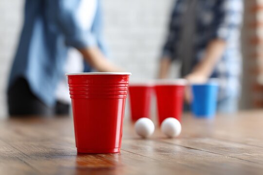 Red party cups and ping pong balls wait on wooden table for fun festival game celebration