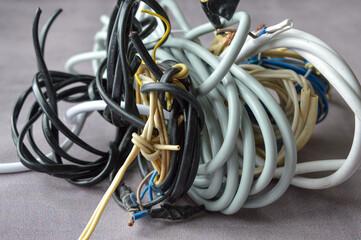 Hand holding a bundle of tangled electrical wires of different colors and thicknesses. Perfect for...