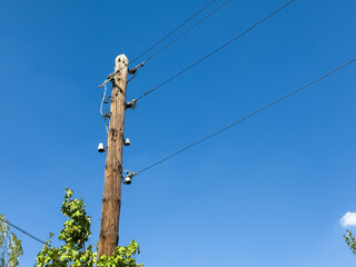 Street wooden pole, pole made of wood, telephone pole, wires on the pole. A tall wooden pole with...