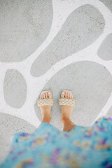 Naklejka premium Feet in Woven Sandals on Patterned Concrete