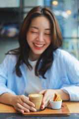 Close up Asian woman hands holding a cup of hot coffee at modern cafe, representing freelance lifestyle, digital nomad, and online business success