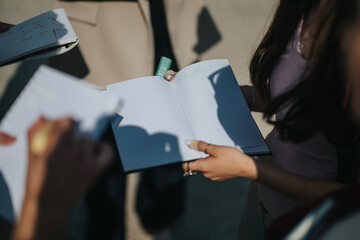 Group of individuals collaborating on educational material outside, sharing notes and solving problems. Learning activity moments outdoors.