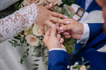 Close-up of a groom placing a wedding ring on the bride’s finger during a wedding ceremony,...