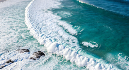 Aerial top down view of a powerful turquoise ocean wave crashing.