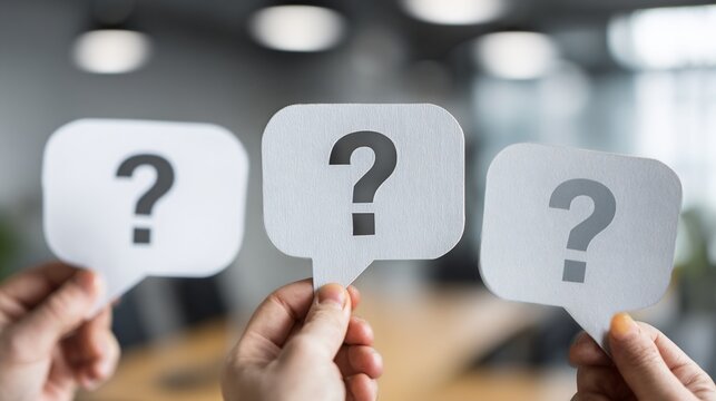 Hands holding up three white question mark speech bubbles