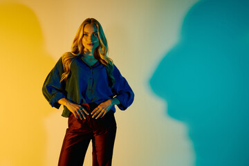 Stylish young woman showcases vibrant fashion in artistic light setting