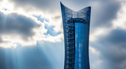 Futuristic blue glass skyscraper with a unique curved design against a dramatic cloudy sky.
