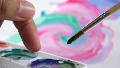 Naklejka premium Close Up of Hand Dipping Paintbrush into Watercolor Palette
