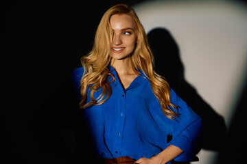Young stylish woman radiates confidence in a vibrant blue shirt during a chic indoor gathering