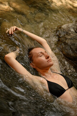Portrait of a young woman with face half submerged in natural water, highlighting her pure beauty, calmness, and organic connection with nature.