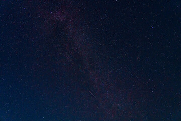Photograph of the night sky with fragment of the Milky Way galaxy with falling meteorite and purple glow. Astronomy as science: study of celestial bodies, stars, meteors, asteroids and other objects