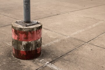 Concrete pole base with red and white stripes in parking lot