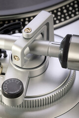 Macro photo of silver tonearm with counterweight and anti-skating adjustment dial on turntable,...