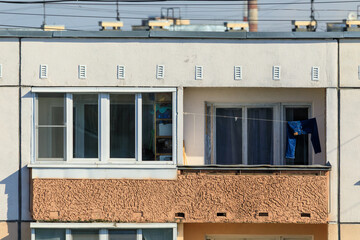 Old apartment building balcony with jeans hanging to dry on a clothesline, showing urban lifestyle and modest residential living conditions.