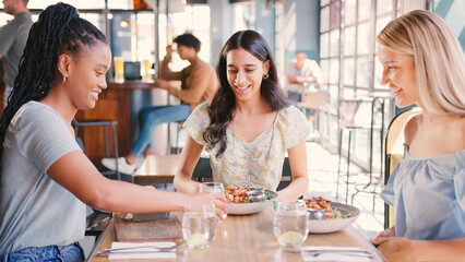 Group Of Female Friends Meeting Up In Restaurant Enjoying Meal Together