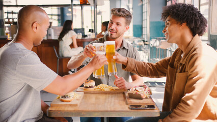 Group Of Male Friends Meeting Up In Bar Doing Cheers With Beer Before Meal