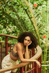 Stylish young woman in leopard print outfit enjoying tropical vibes with lush greenery