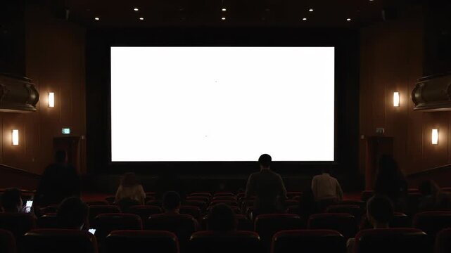 Empty Movie Screen in Dark Theater - A large, blank movie screen is shown in a darkened theater. The audience is seated, awaiting the film's start. The overall mood is one of anticipation.