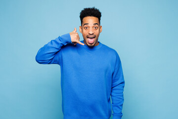 Young man of African American ethnicity wear sweatshirt casual clothes doing phone gesture like...