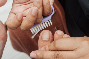 A small brush is used to clean the toenail during a foot spa treatment, part of the grooming phase...