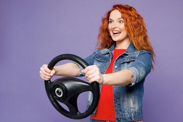 Side view young smiling ginger woman she wears red t-shirt denim shirt hold steering wheel driving...