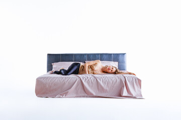 A woman carefully arranges light pink bed linen on a modern bed. The bright and minimalistic...