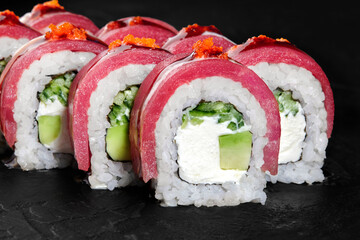 Philadelphia uramaki sushi rolls with tuna and tobiko on dark background