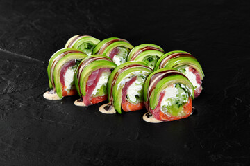 Delicious uramaki sushi rolls with salmon, tuna, avocado, and cream cheese on black background