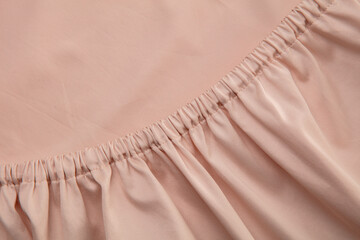 A close-up view of soft, pale pink fabric reveals a gathered texture that adds depth and interest,...
