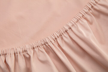 A close-up view of soft, pale pink fabric reveals a gathered texture that adds depth and interest,...