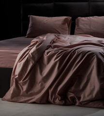 Soft pink bedding is elegantly draped over a sleek black bed frame in a cozy bedroom, illuminated...