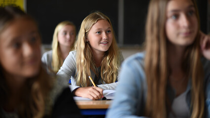 a young woman sitting at a desk in a classroom, smiling. student studying at university, back to school, classes at university