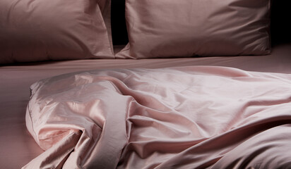A beautifully arranged soft pink bedding is draped over a modern bed in a stylish bedroom. The...