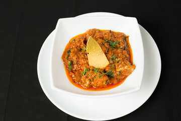 Chicken Tikka Masala Garnished with coriander on a White Plate isolated on black background top view of Indian Curry Dish
