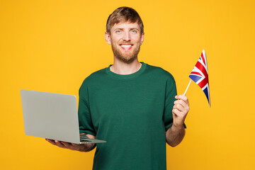 Young smart smiling happy IT man he wear green t-shirt casual clothes hold American flag use work...