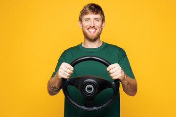 Young smiling happy cool Caucasian man he wear green t-shirt casual clothes hold steering wheel...