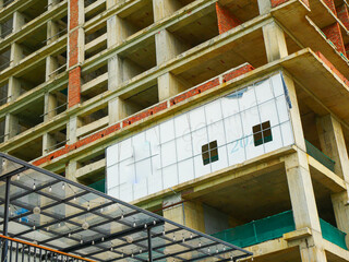 Multi-story concrete and brick building features glass ceiling on lower level, scaffolding, and signage announcing opening, blending hospitality design with active construction in Danang