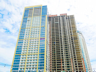 Modern yellow-blue tower with glass modern facade contrasts exposed concrete structure under construction, highlighting urban growth and architectural transformation in dynamic urban Danang