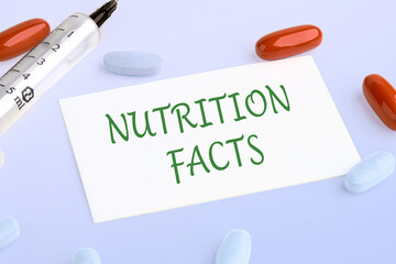 Nutrition facts text written on the business card next to pills, vitamins and a syringe