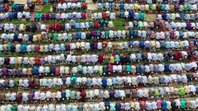 Dinajpur, Bangladesh - 24 August 2025: Aerial view of many people praying, their colorful clothes creating a vibrant pattern on the green field.