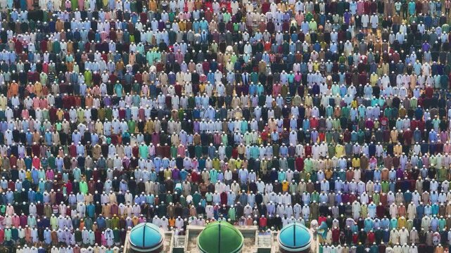 Dinajpur, Bangladesh - 24 August 2025: Aerial view of a sea of people praying in unison, creating a mesmerizing pattern of colorful garments and white prayer caps.