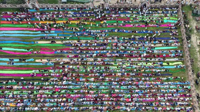 Dinajpur, Bangladesh - 24 August 2025: Aerial view of people gathered for prayer on colorful mats at Eidgah ground, a vibrant display of faith and community.