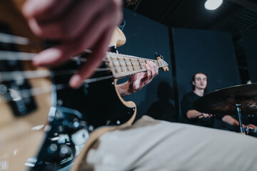 Close-up view of a bassist playing while rehearsing with a drummer for a performance.