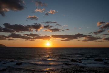 海に沈む太陽とオレンジ色に光る雲
