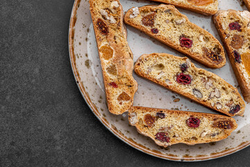 Italian Almond Biscotti biscuits in a rustic home made pottery bowl. Studded with almonds and cranberries, these twice-baked treats are aromatic and inviting. Ideal.
